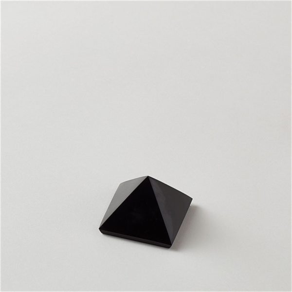 A jet black carbon stone, cut and polished into a pyramid shape