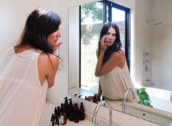 woman in bathroom looking at self in mirror
